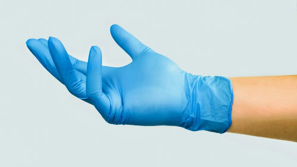 Hand in a light blue disposable glove