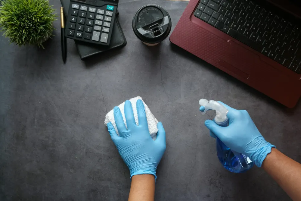 Wiping a desk in blue gloves